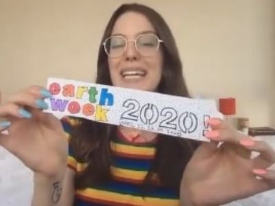 Eleanor Lambert is holding the piece of paper that says earth week 2020 which is written by her.